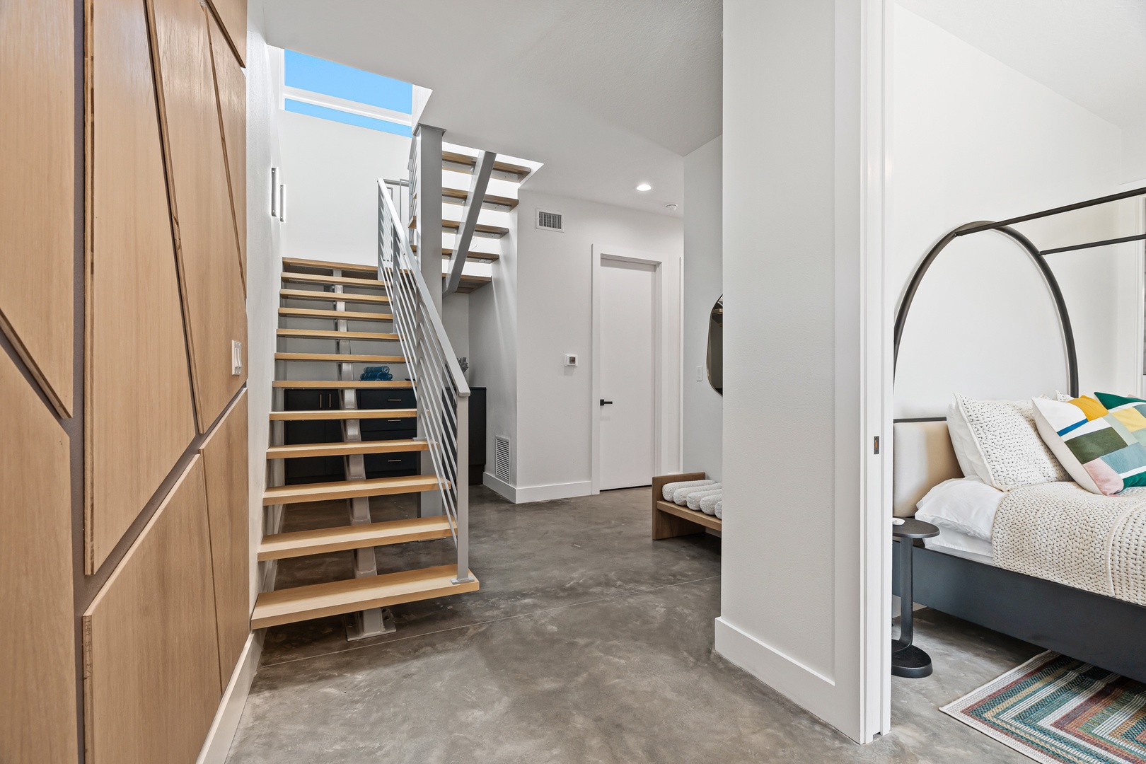 Bright, open hallway connects your living spaces with a stunning modern staircase bathed in natural light from above. Clean lines and thoughtful design create an inviting flow throughout your home.