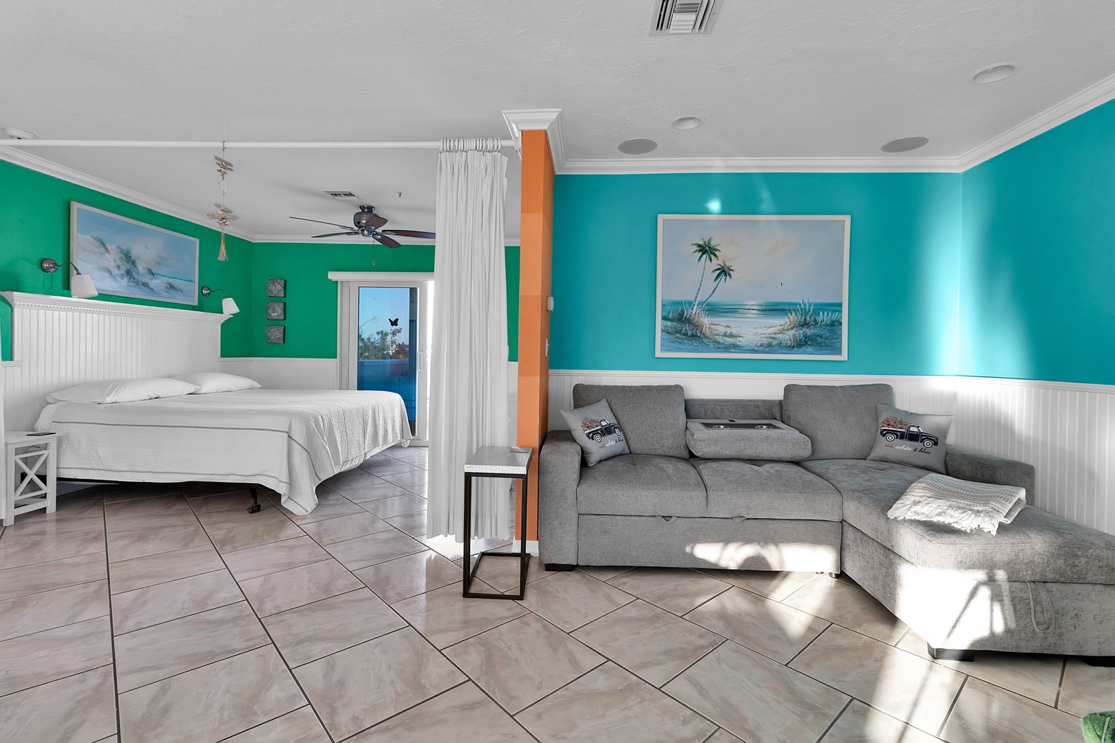 Relax in your bright, open-plan space where coastal color meets comfort. The plush sofa invites lazy afternoons while the crisp white bed awaits restful nights under the ceiling fan's gentle breeze.
