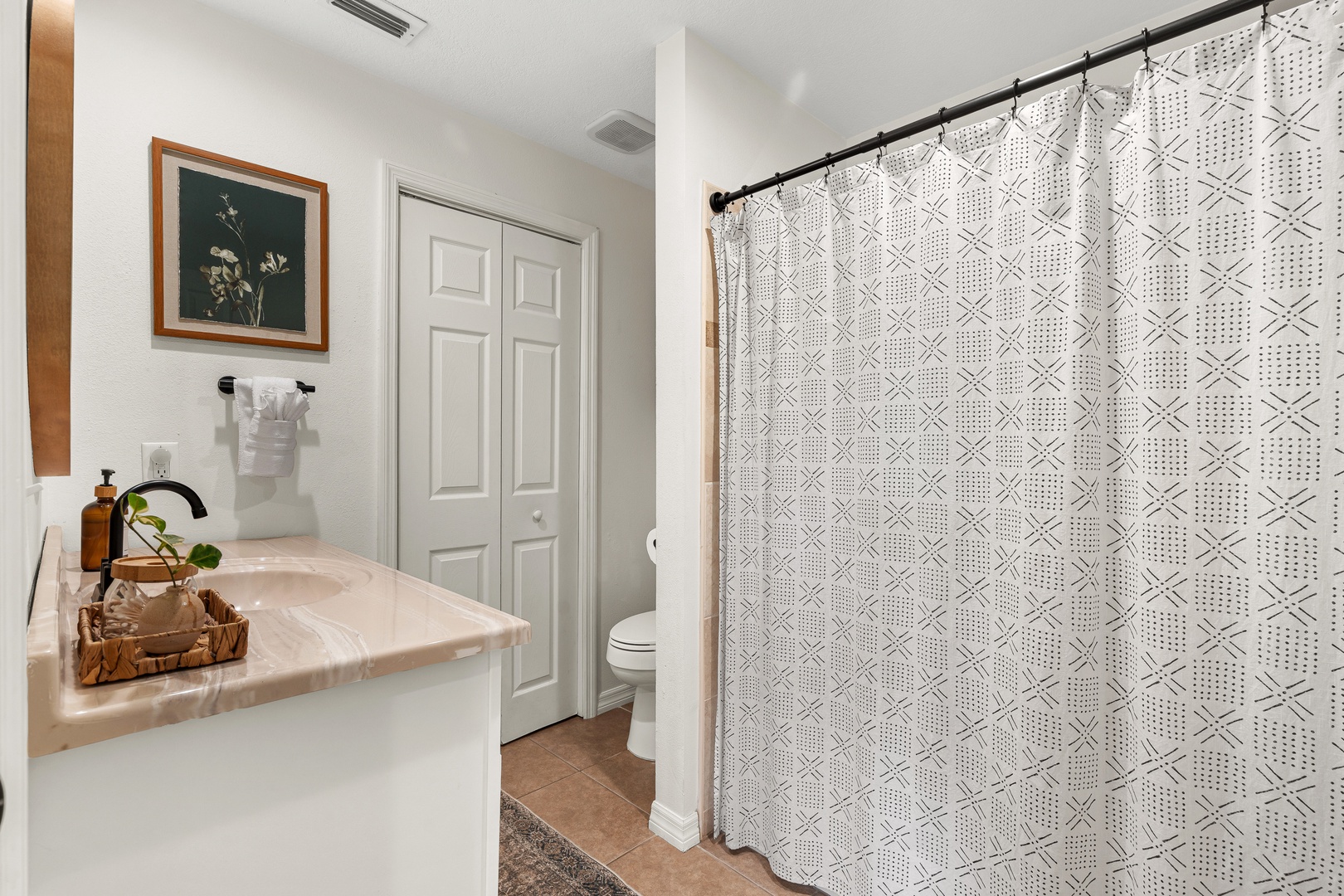 Freshen up in this tastefully appointed bathroom with modern fixtures, elegant vanity, and a spacious walk-in shower behind a stylish curtain.