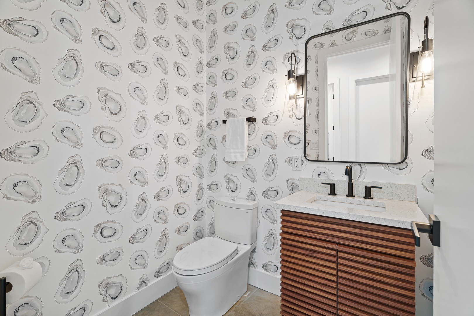 Freshen up in your stylish powder room with coastal-inspired wallpaper, modern fixtures, and a sleek vanity that adds warmth to your space.