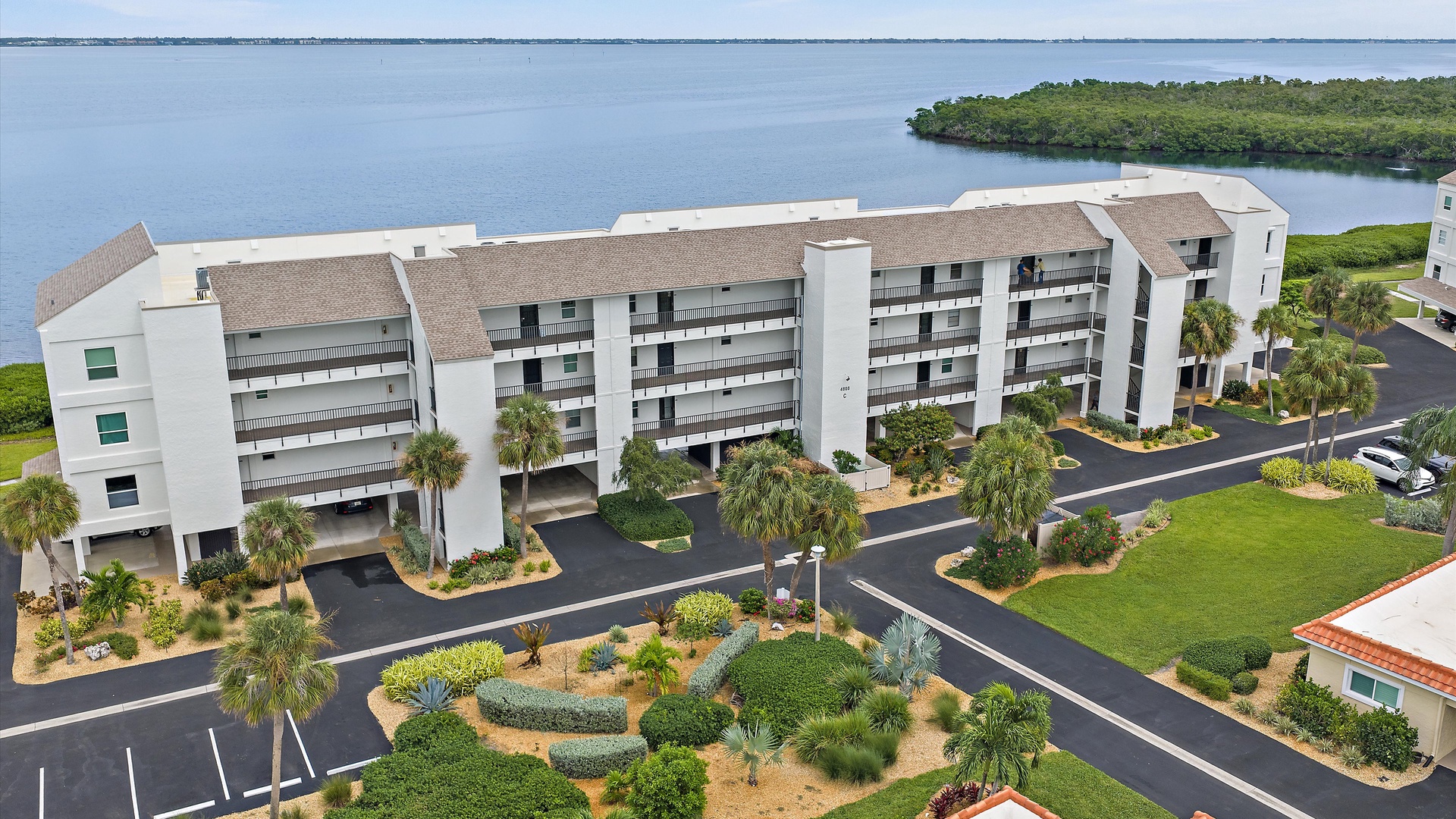 Windward Bay’s waterfront setting comes into focus from above: Sarasota Bay behind the building, with palms and landscaped grounds below. A beautiful location for an extended Longboat Key stay.