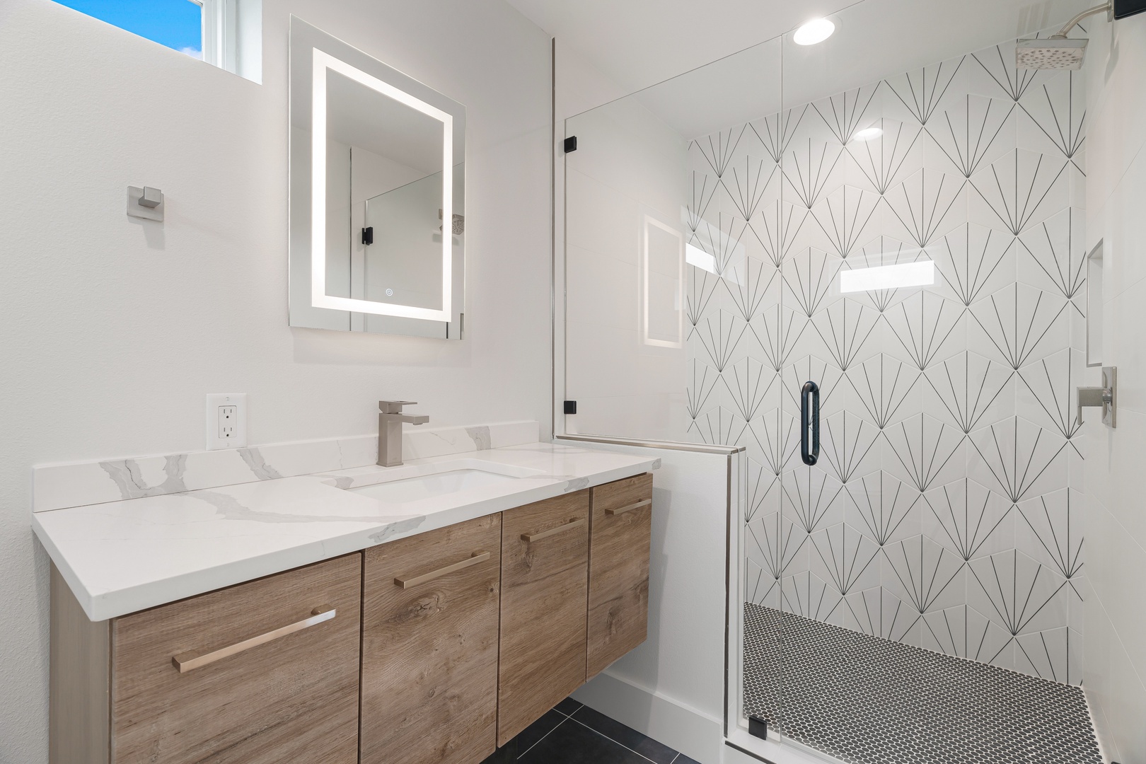 Step into your private spa-inspired bathroom, where a sleek walk-in shower with stunning geometric tile awaits. The bright, modern vanity with dual sinks offers plenty of space for your morning routine.