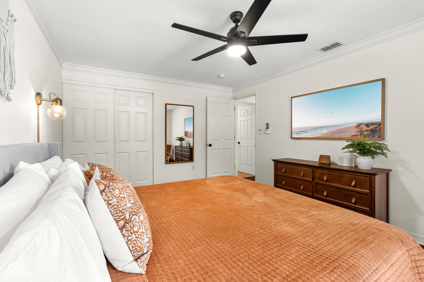 Sink into crisp linens beneath a coastal landscape and let the ceiling fan's gentle breeze lull you to sleep after sun-soaked days by the water.