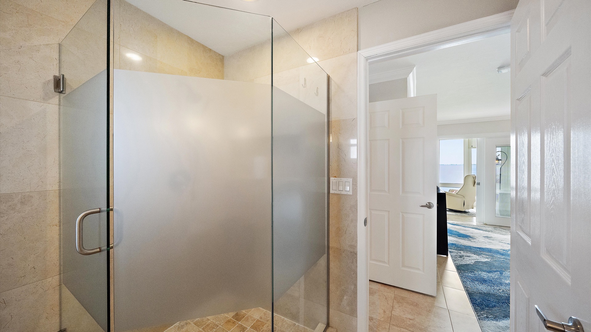 A glass-enclosed shower and warm tile finishes complete the primary bathroom. Its connection to the king bedroom keeps the suite comfortable and self-contained.
