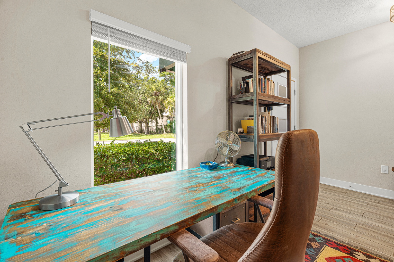 Your workspace overlooks the neighborhood's lush greenery through a large window, while a vintage desk and open shelving set a creative, inspiring tone for your stay.
