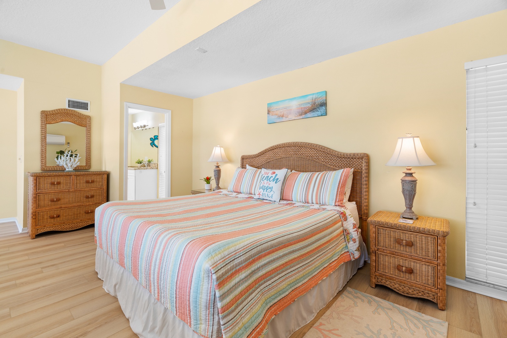 Unwind in your coastal-inspired bedroom, where warm wicker furniture and colorful striped bedding create the perfect beach retreat.