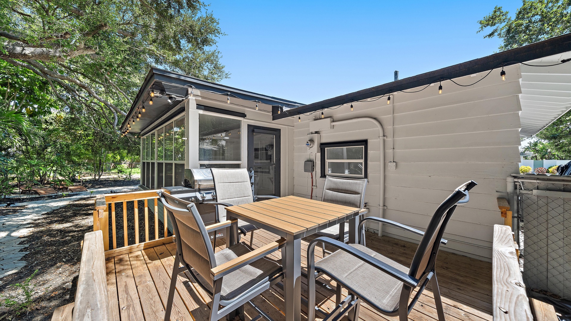 Step onto your private deck and enjoy outdoor meals surrounded by natural greenery. This inviting patio offers comfortable seating, warm lighting, and a peaceful setting perfect for morning coffee or evening gatherings.