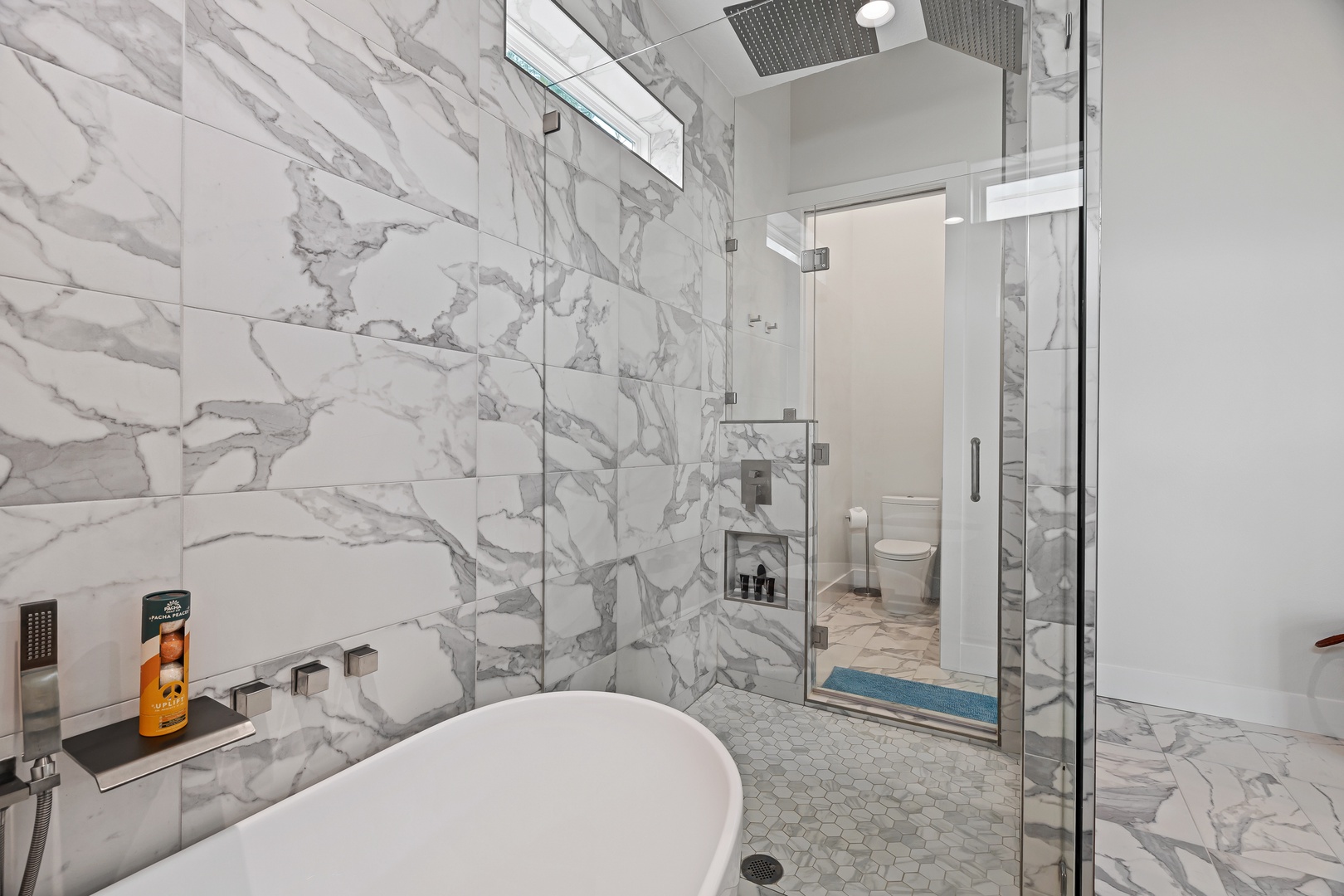 Slip into your spa-like sanctuary with a sleek freestanding tub, spacious glass-enclosed shower, and stunning marble-clad walls that wrap you in quiet luxury.