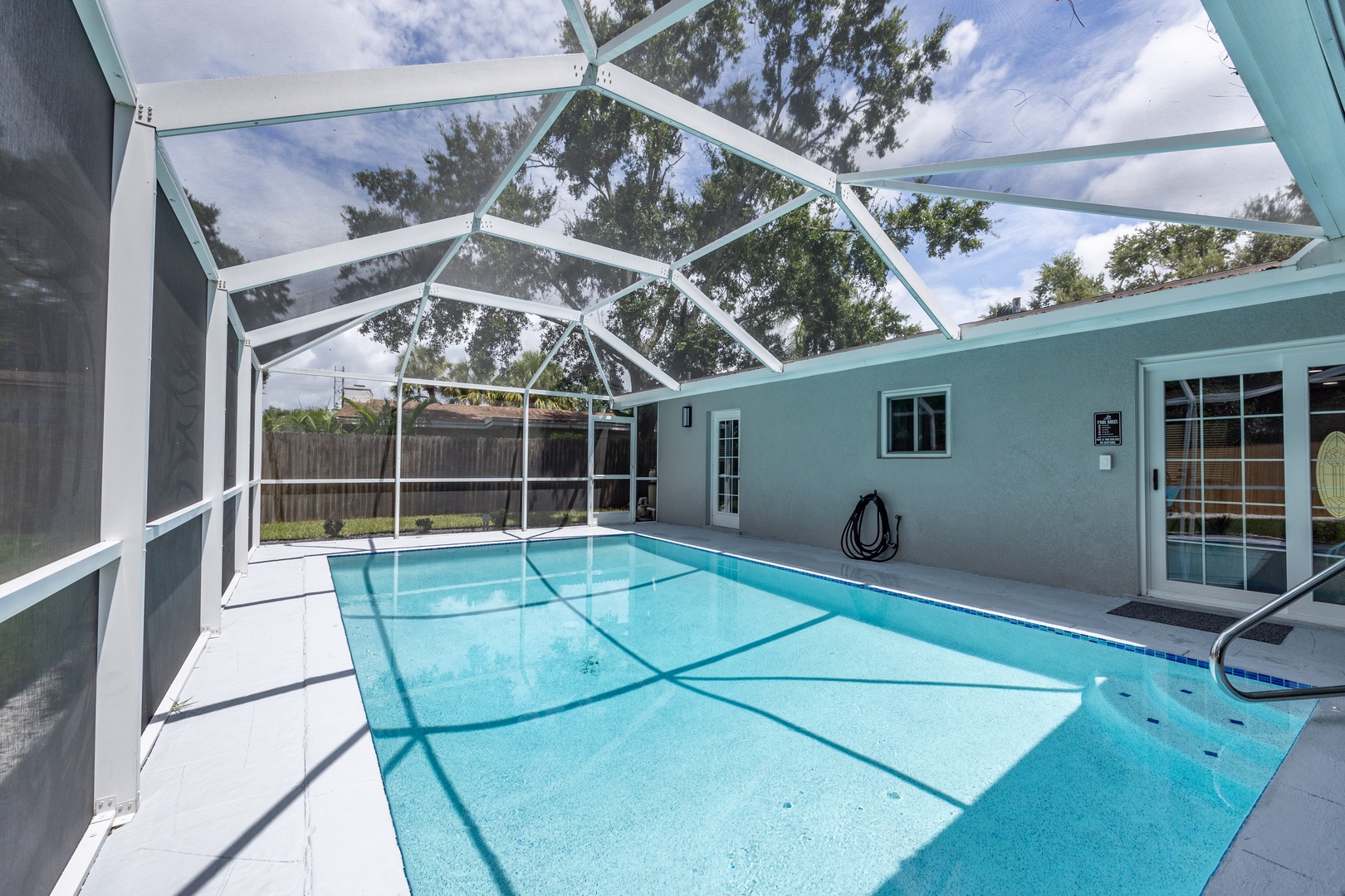 Dive into your private screened pool sanctuary, where crystal-clear water awaits under soaring glass ceilings.
