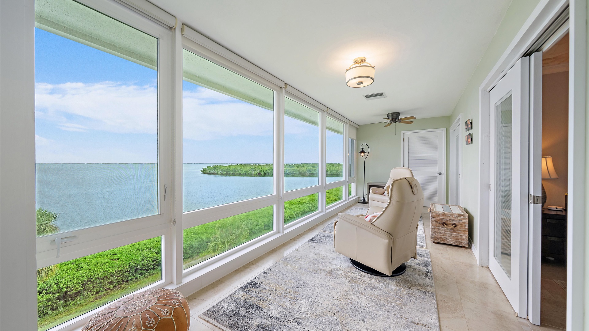 Coffee tastes better with a view like this. Settle into a recliner as Sarasota Bay and the mangrove shoreline fill the windows—your private sunroom for slow mornings and wonderfully lazy afternoons.
