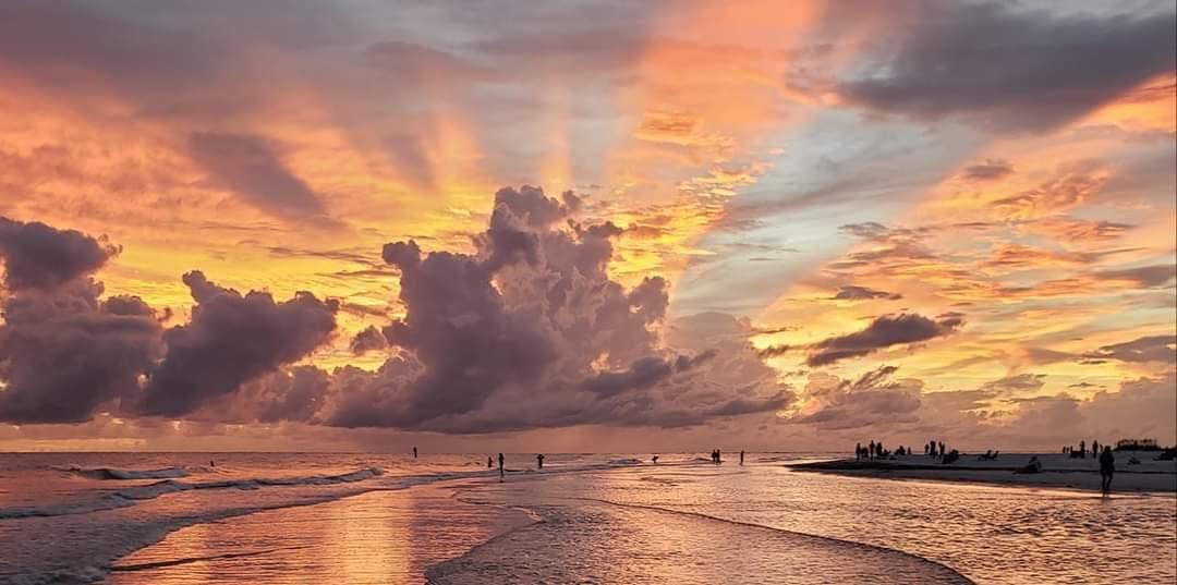 A stunning Siesta Key sunset paints the sky in brilliant oranges and golds, with gentle waves rolling onto the sand as the day comes to a peaceful close.