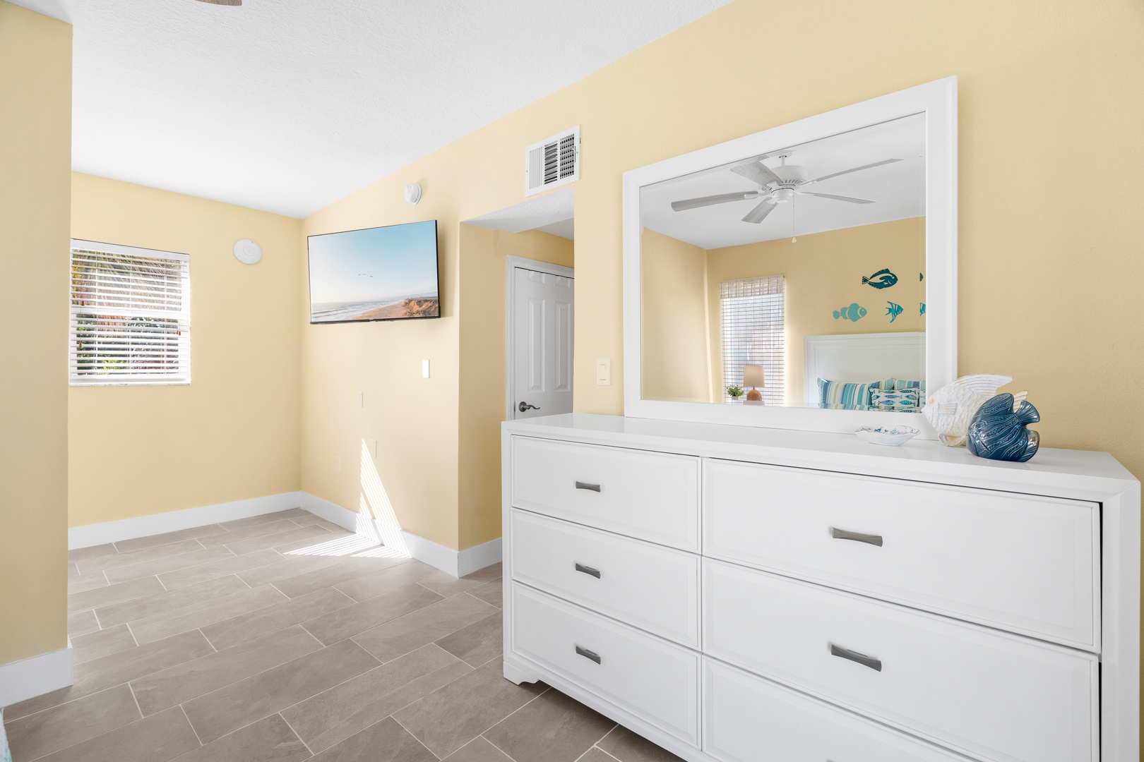 Unpack your belongings in this spacious bedroom with coastal charm, featuring ample dresser storage and cheerful yellow walls that welcome you home.