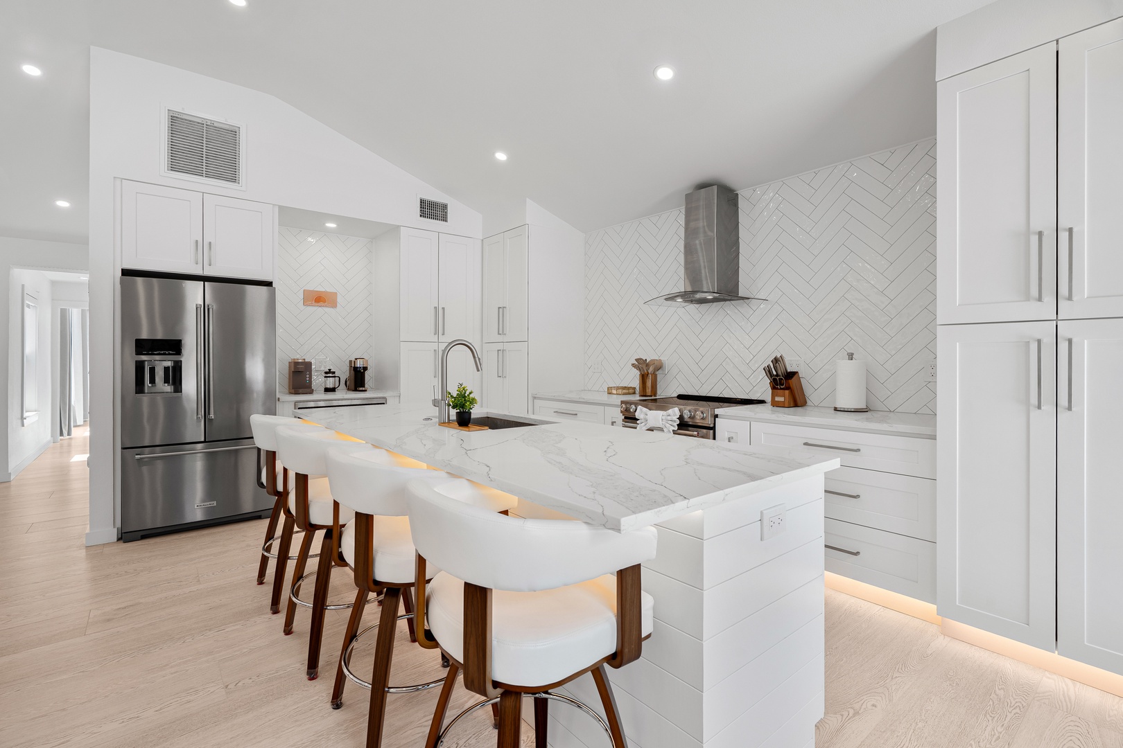 Sleek modern stocked kitchen with island and seating, stainless steel appliances.