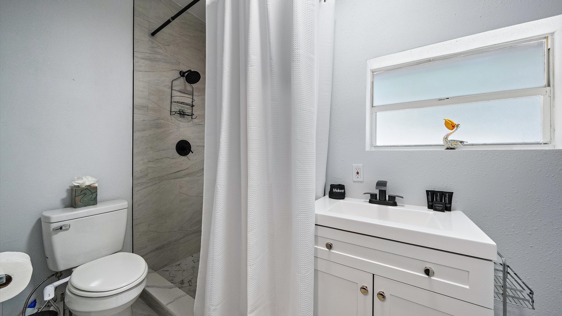 Your private bathroom features modern tile work, a spacious walk-in shower, and a bright, airy feel enhanced by natural light streaming through the window.
