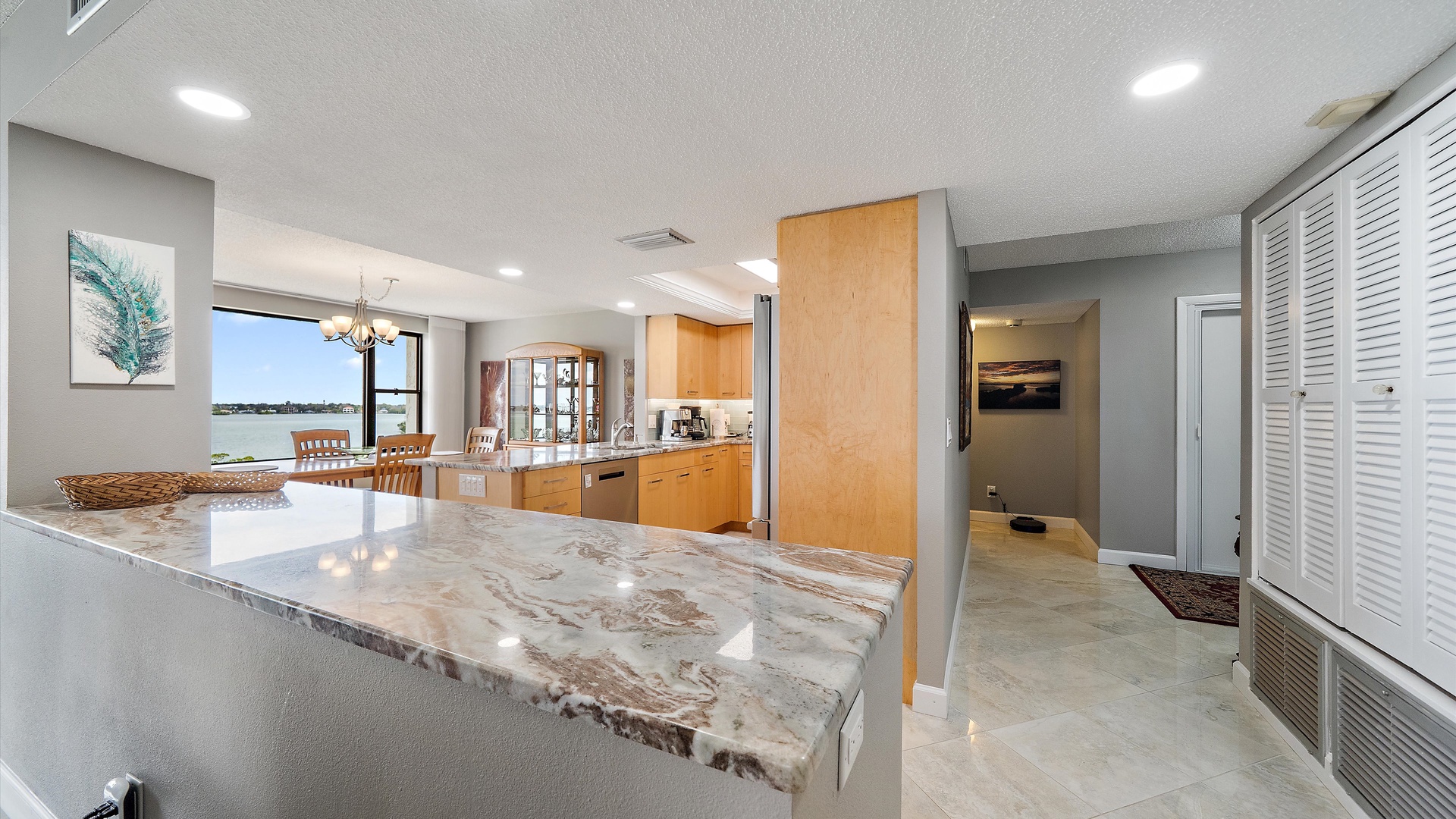 Your spacious kitchen features gleaming marble countertops and warm wood cabinetry, perfect for preparing meals while enjoying stunning water views.
