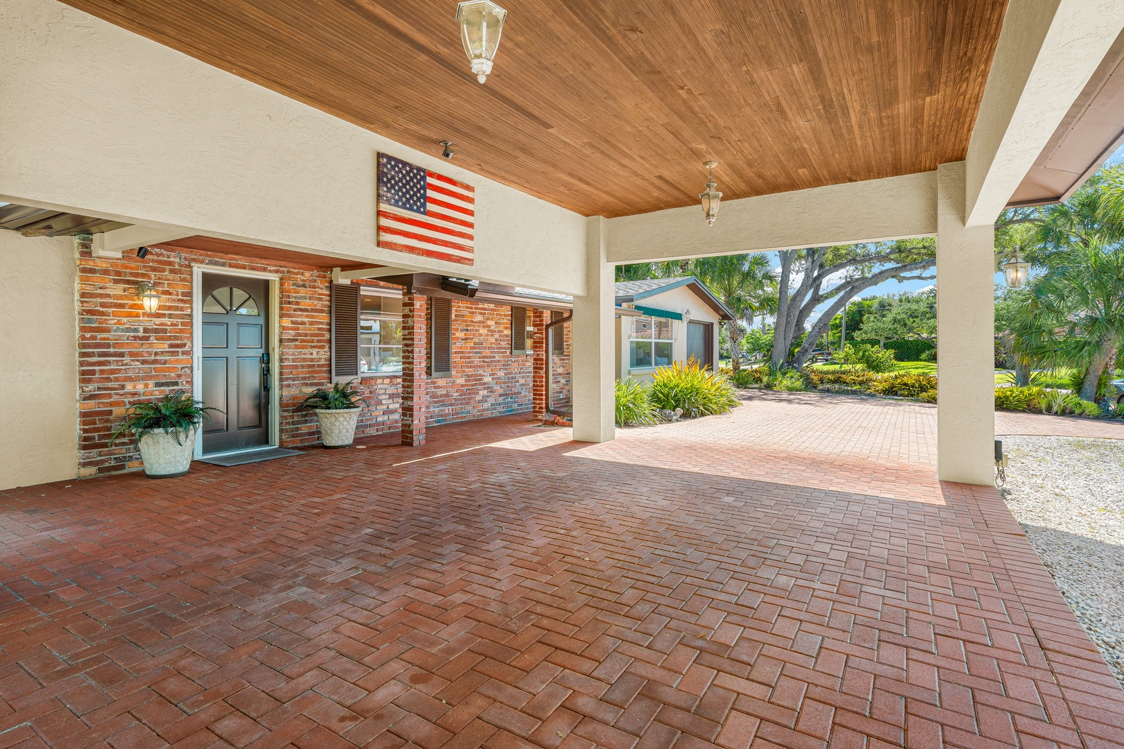 A welcoming covered entrance features rich wood ceilings and classic brick pavers, marking the start of your coastal Florida getaway.