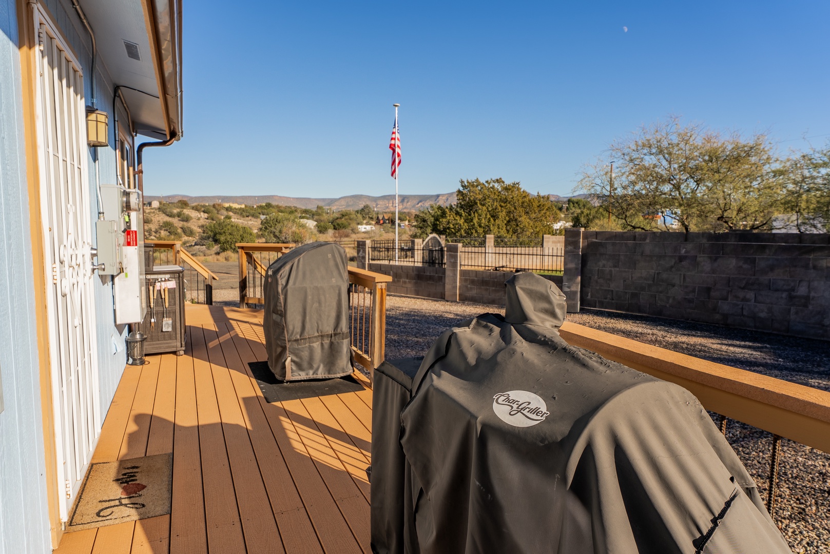 Spacious deck with covered BBQ grill and smoker, perfect for outdoor cooking while enjoying the open desert landscape and mountain views in the distance.