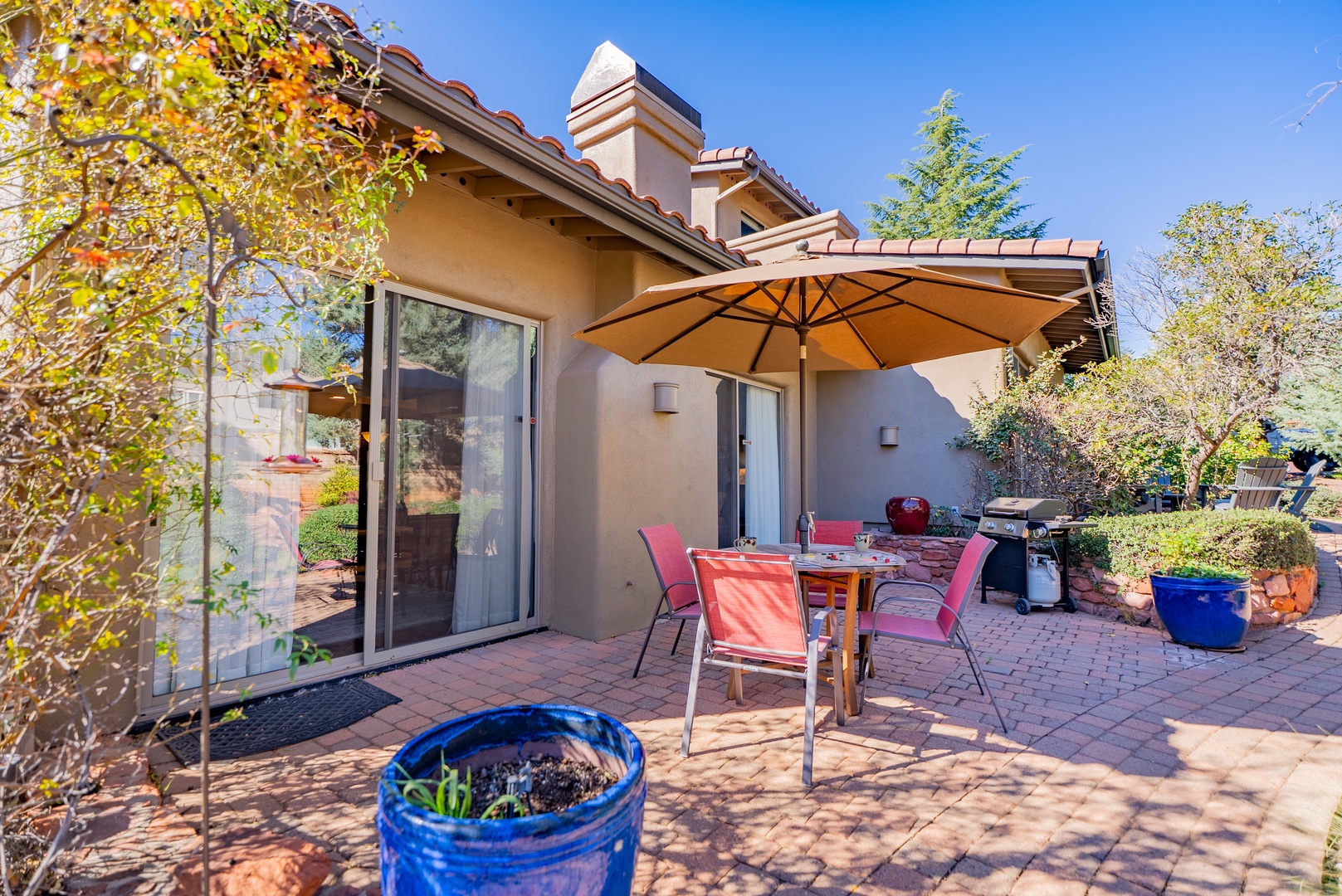 Relax on your private patio with shaded dining under mature trees, where brick pavers and vibrant planters create your perfect outdoor retreat.