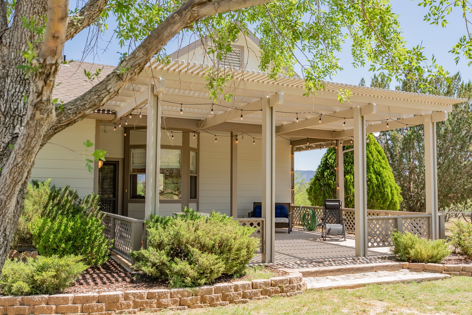 Charming property exterior featuring a covered pergola with string lights and mountain views in the distance.