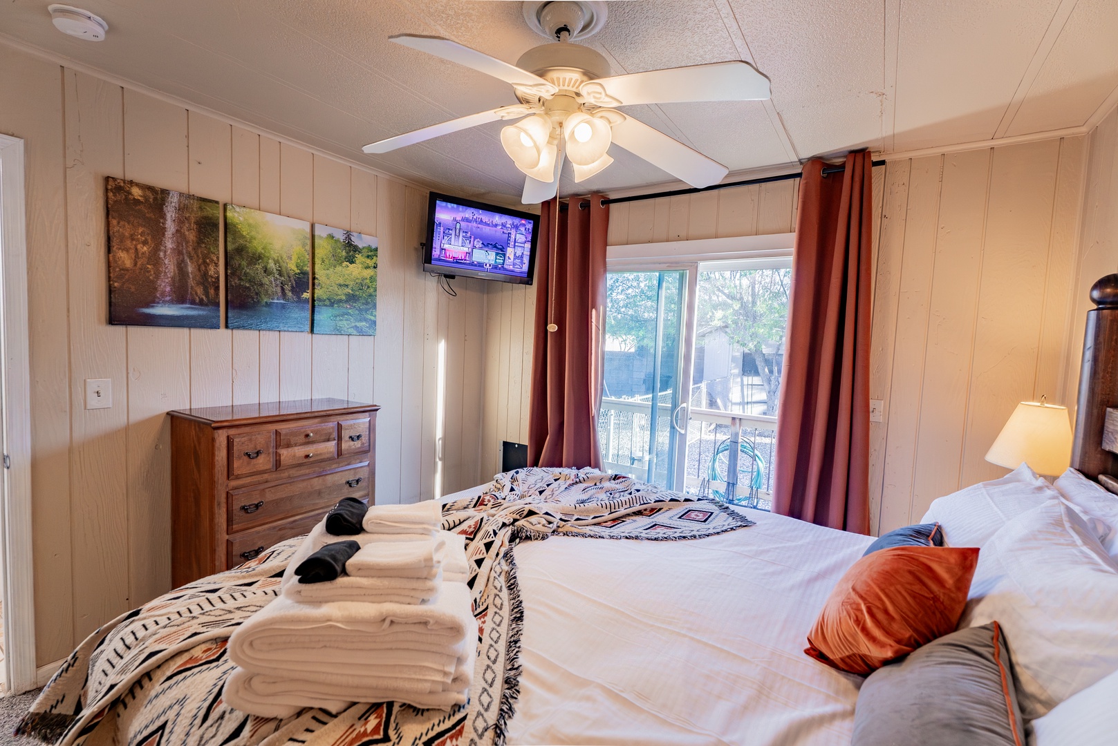 Relax in your comfortable bedroom with cozy lake-themed decor, ceiling fan for gentle breezes, and your own private balcony access for peaceful moments outdoors.