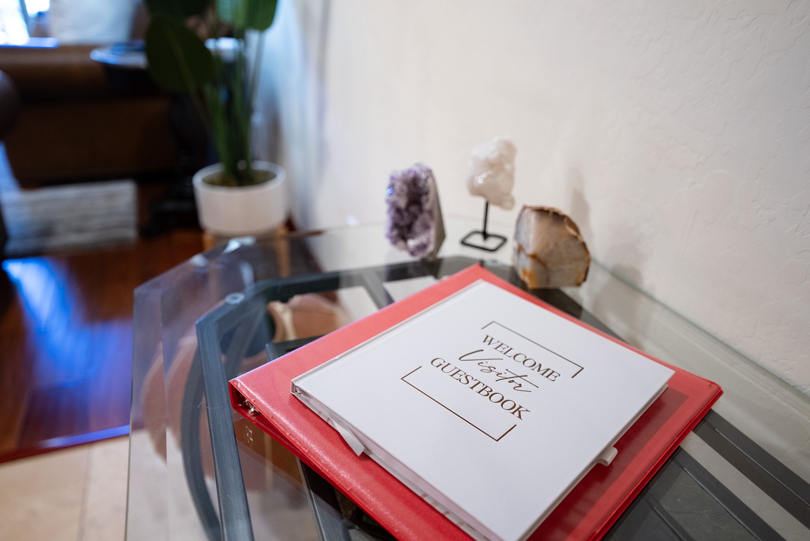 Discover your thoughtfully curated welcome guide alongside natural crystal displays on this elegant glass table in your serene living space.
