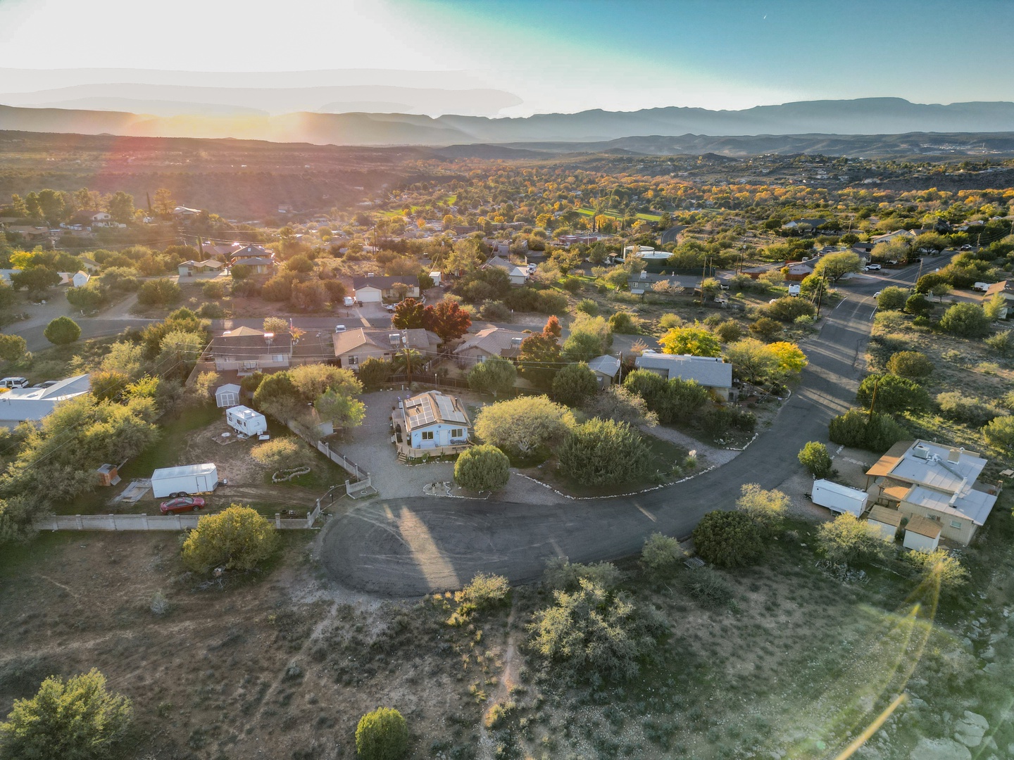 Aerial view of the peaceful residential neighborhood surrounding the property, with rolling hills and mountains in the distance.