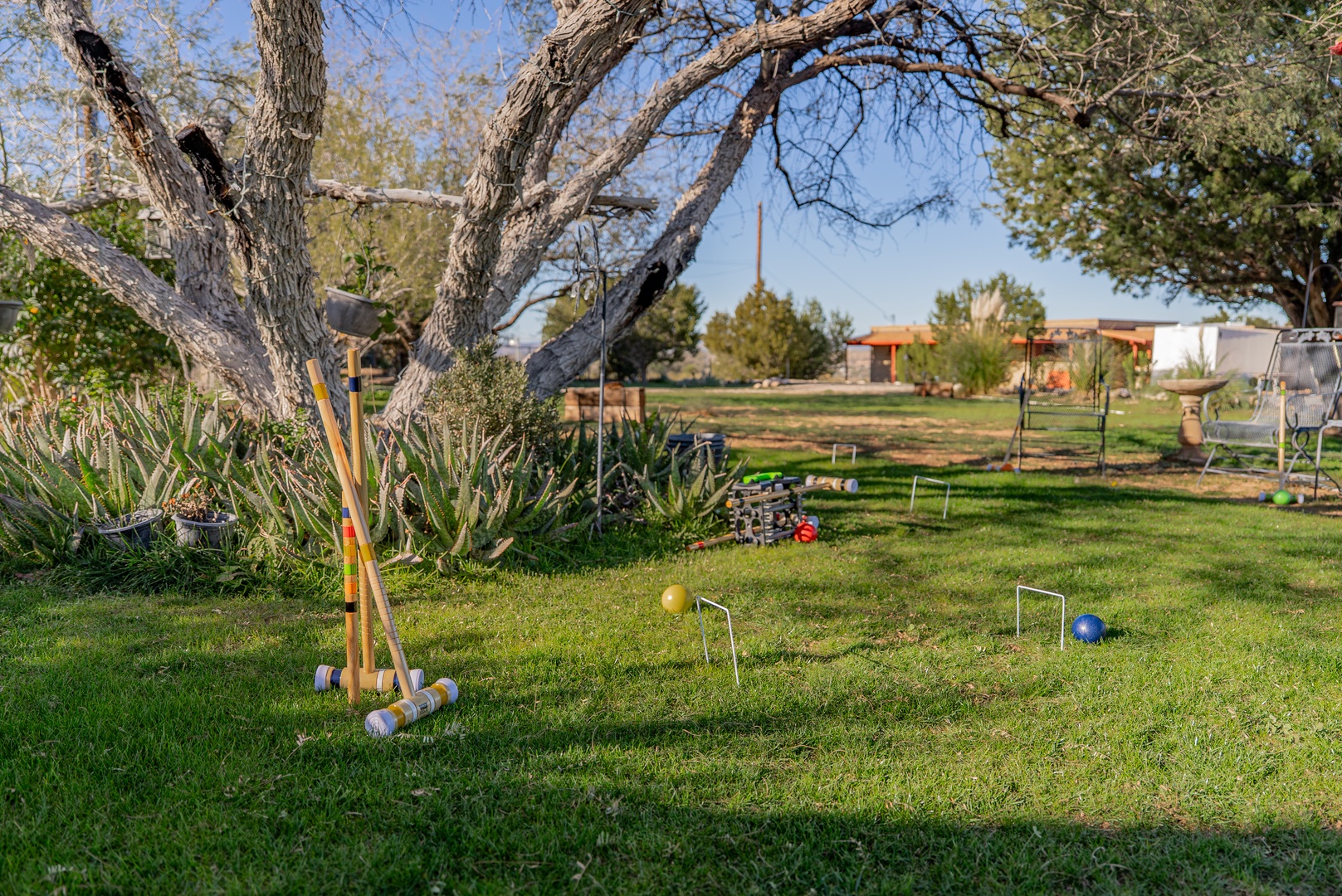A sunny lawn area with croquet equipment set up for outdoor games and recreation in a peaceful property setting.
