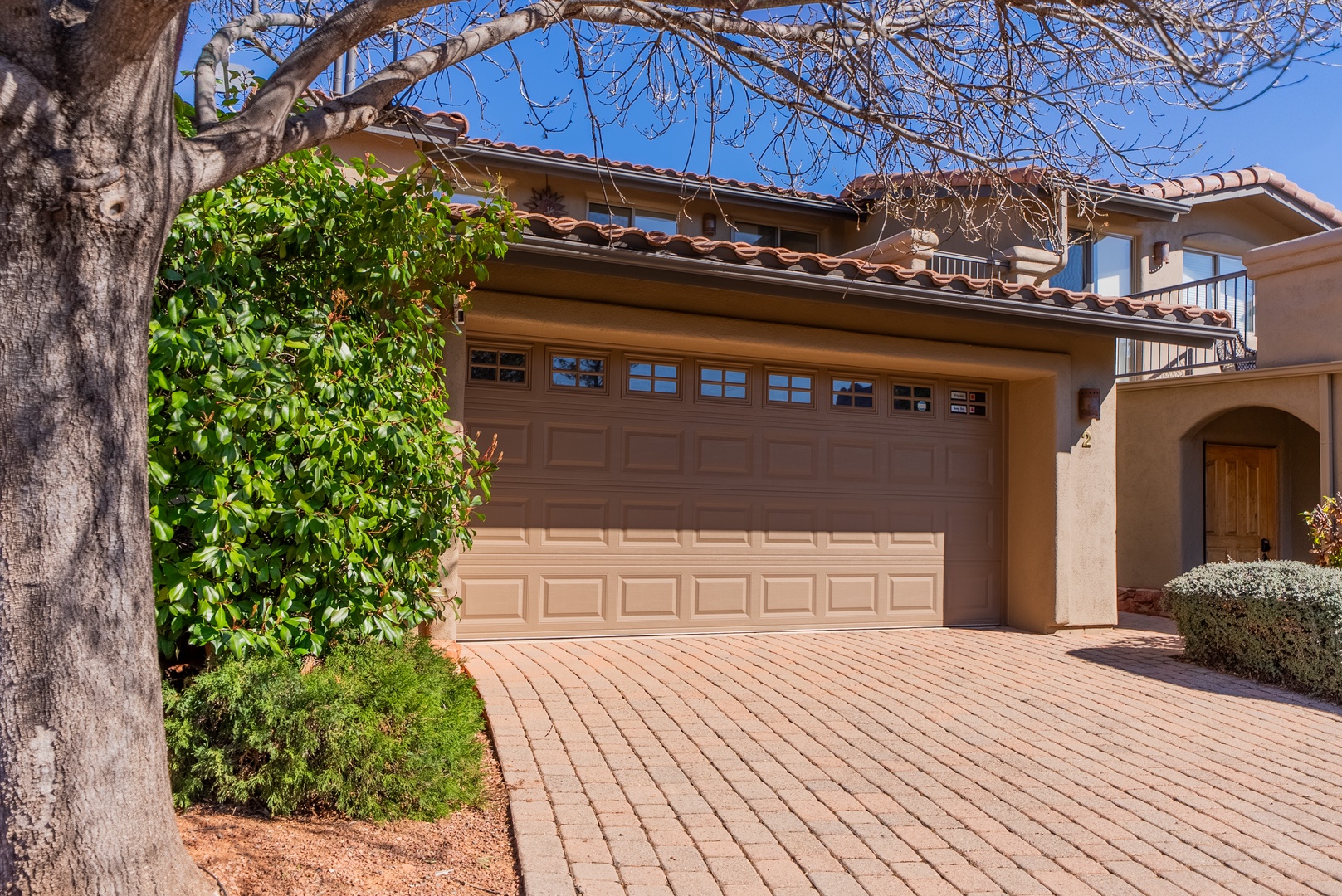 Beautiful Mediterranean-style home with charming tile roof, mature landscaping, and convenient garage parking in a peaceful residential setting.