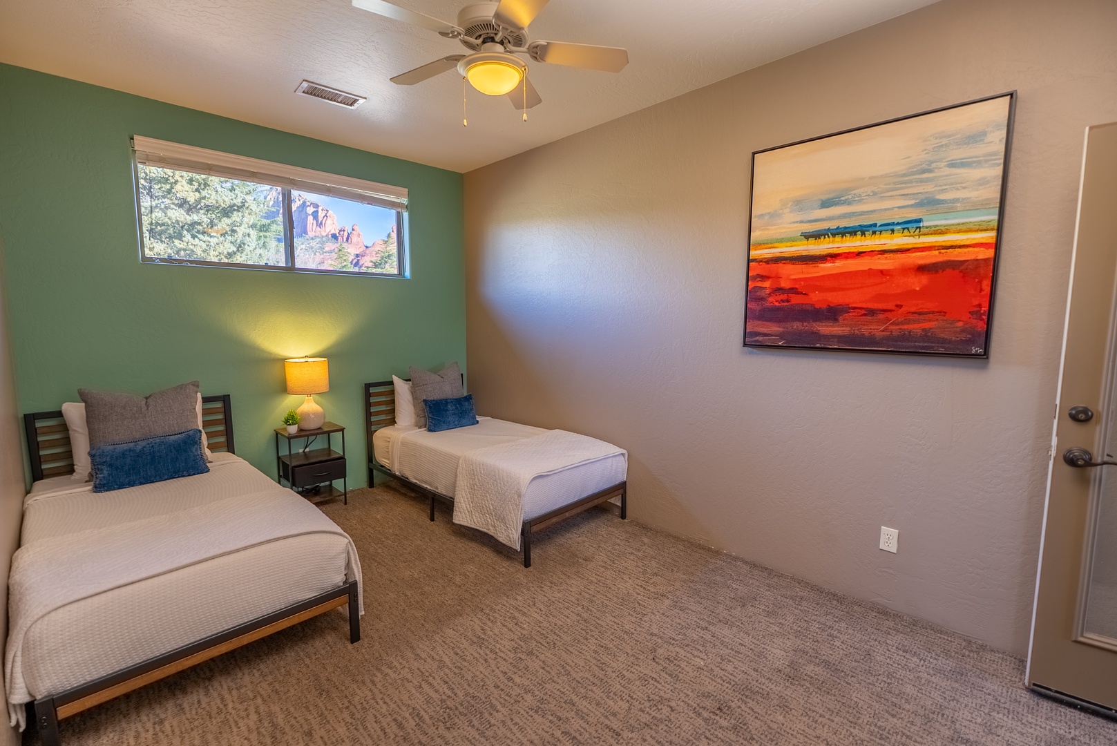 Rest peacefully in your twin bedroom with warm earth tones, vibrant artwork, and a gentle ceiling fan for comfort.