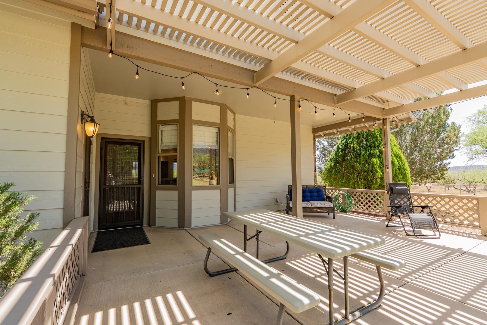 Relax under your private covered patio with string lights creating perfect ambiance for outdoor dining and unwinding.