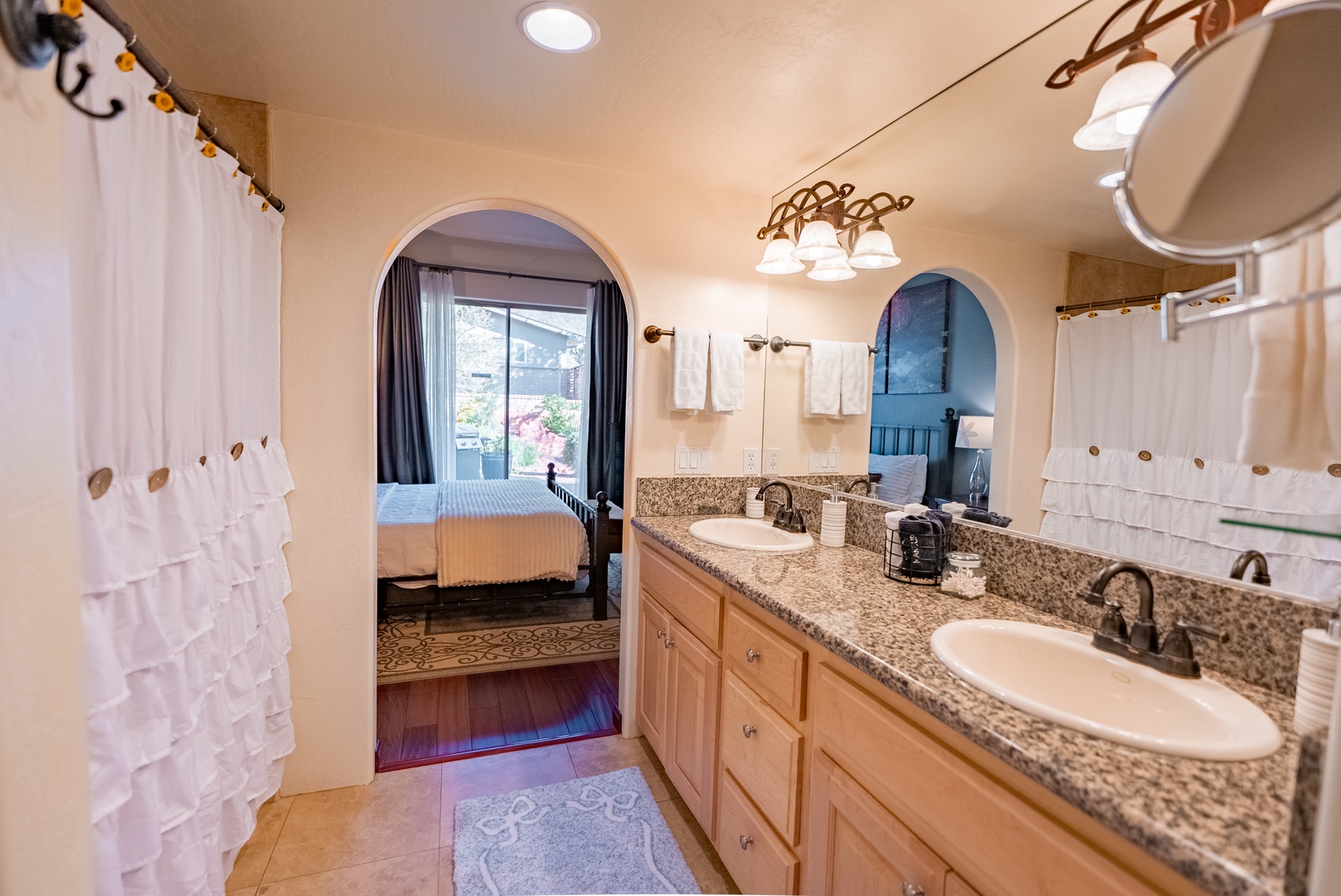 Your spacious ensuite bathroom features dual vanities with granite countertops, elegant archway details, and connects seamlessly to your peaceful bedroom retreat.