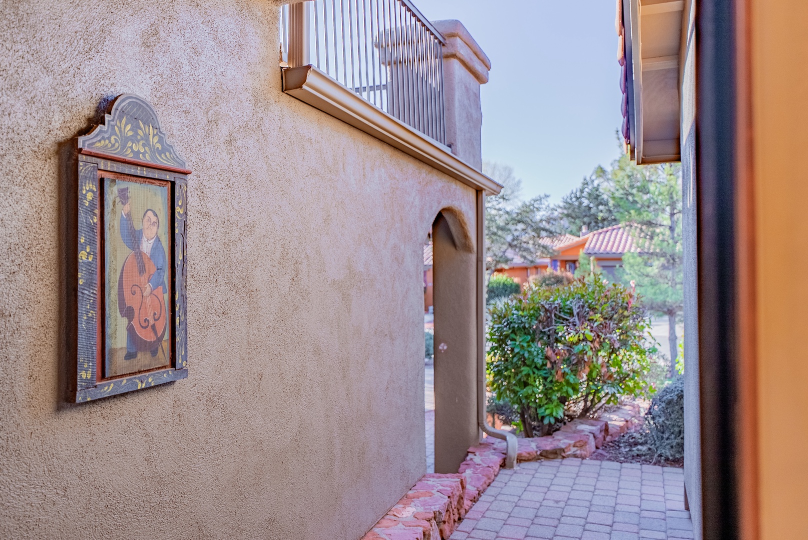 A charming southwestern-style courtyard with decorative tile artwork and lush landscaping creates a peaceful entrance to your desert retreat.