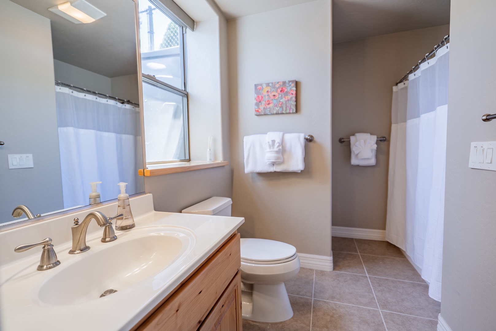 Freshen up in your modern bathroom with dual sinks, natural light, and pristine towels waiting for you.