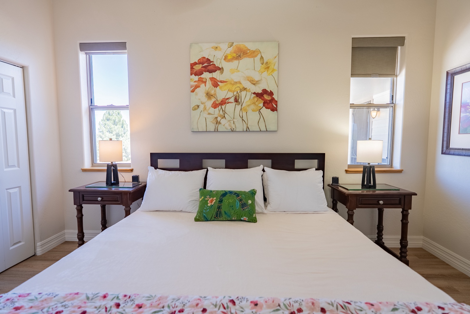 Sink into crisp white linens in your peaceful bedroom, where warm natural light and charming artwork create the perfect retreat.