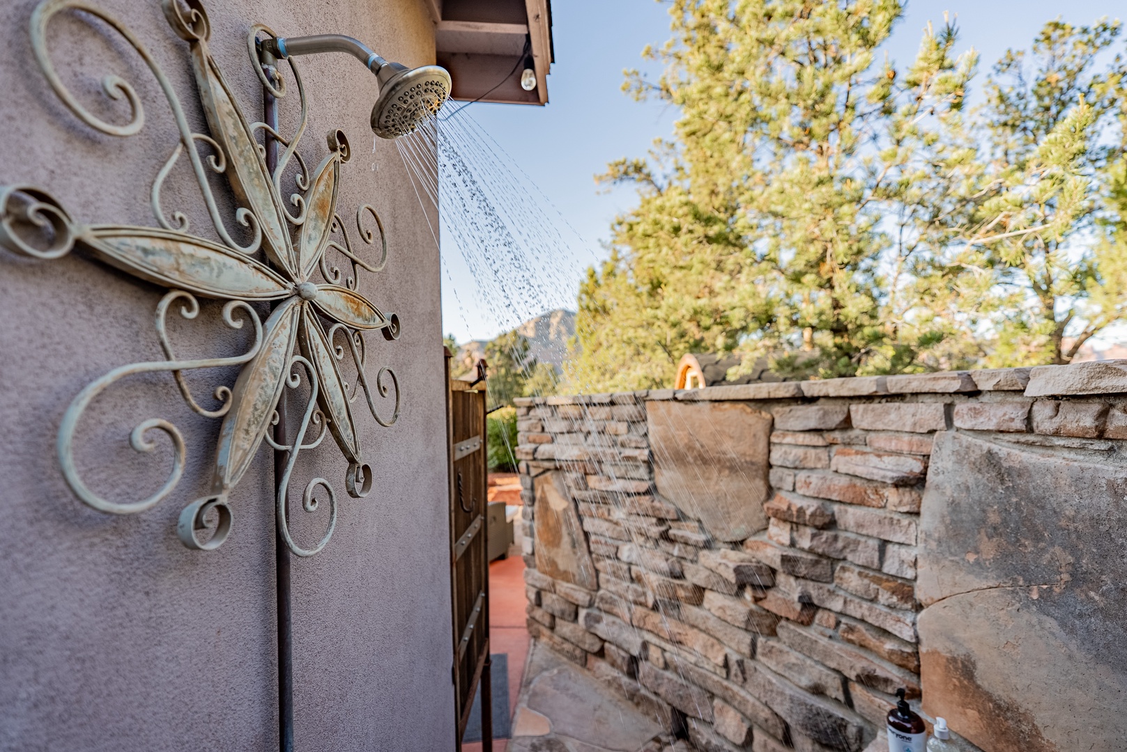 Outdoor shower, framed by stacked stone privacy pre and post sauna and tub