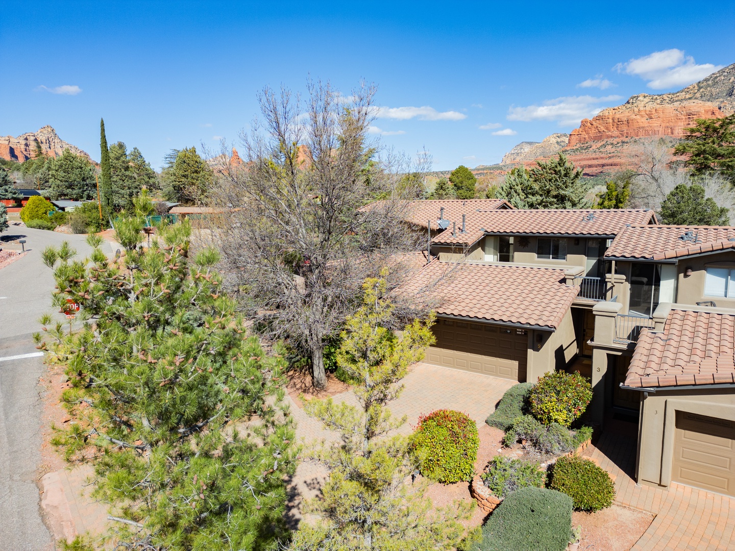 Stunning red rock formations frame this desert retreat, nestled among vibrant landscaping in a peaceful residential setting.