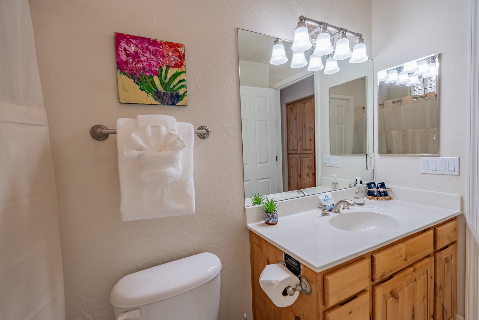 Your pristine bathroom awaits with modern lighting, thoughtful amenities, and warm wood vanity - perfect for refreshing after adventures.