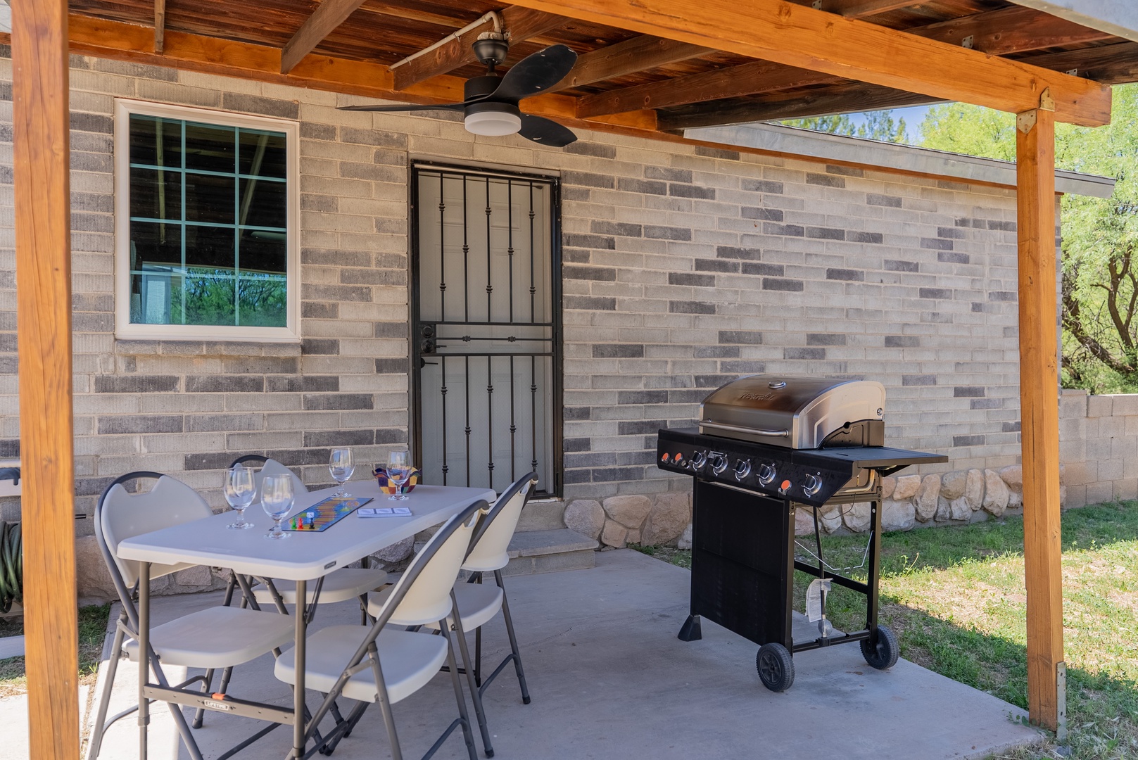 Outdoor patio and grill, access to shed has folding table, chairs and grilling tools.