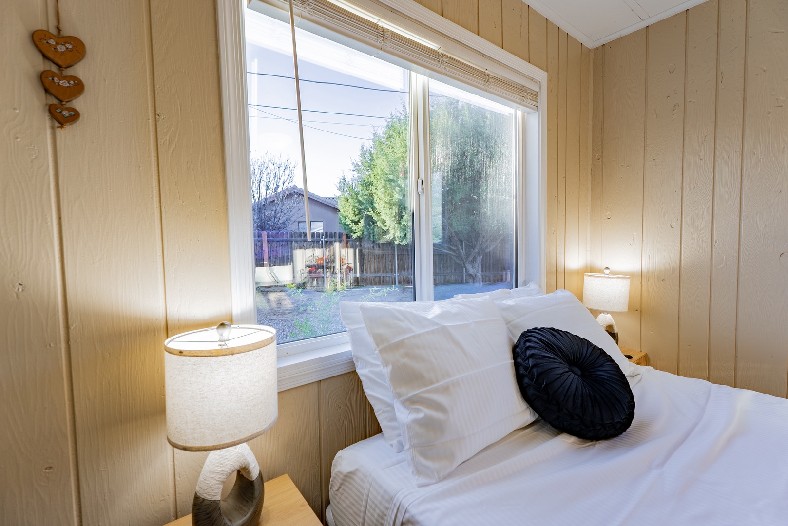 Drift off peacefully in your cozy bedroom with warm wood paneling, crisp linens, and natural light streaming through your window overlooking the quiet neighborhood.