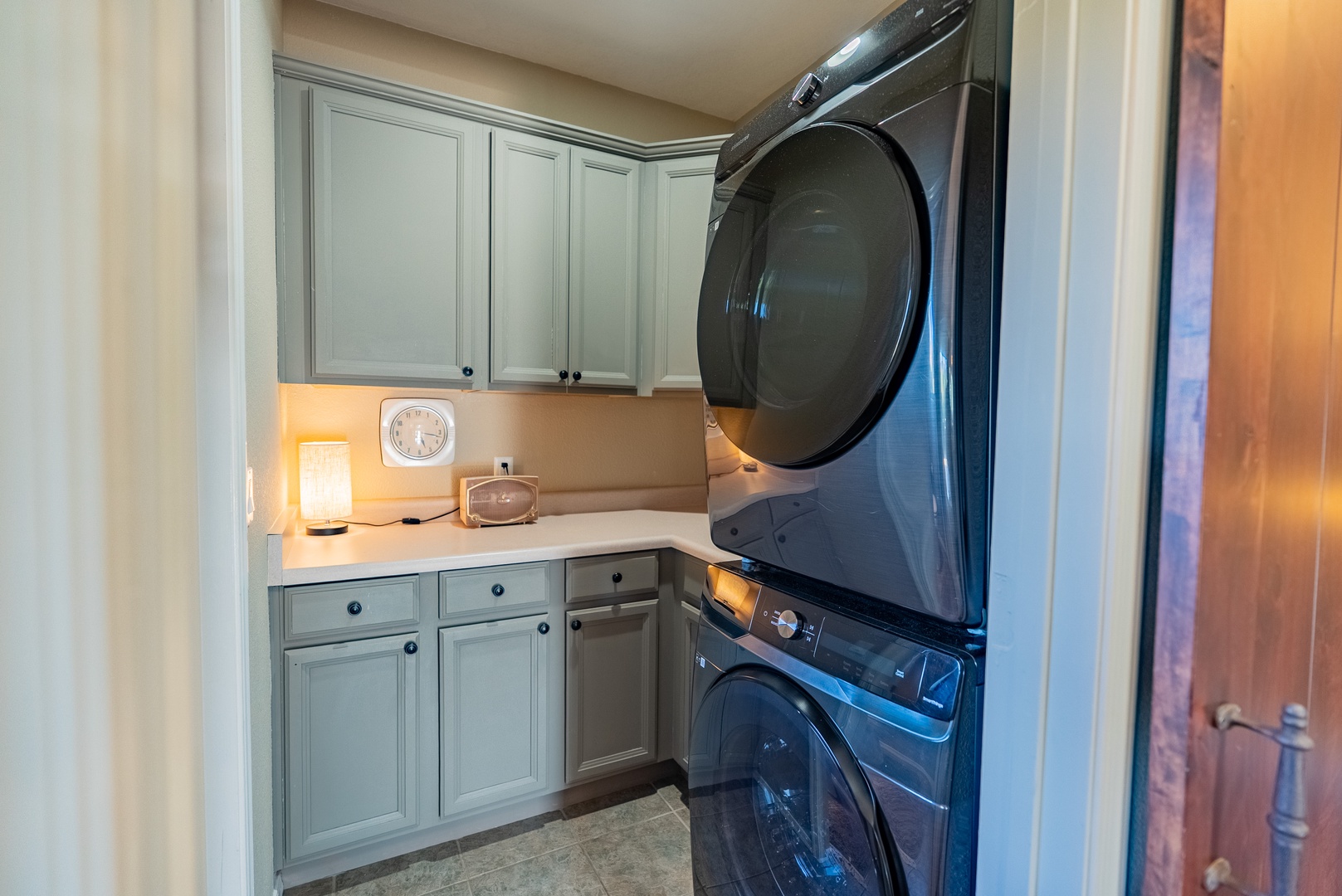 Stacked washer dryer in laundry room also stores specialty drinkware