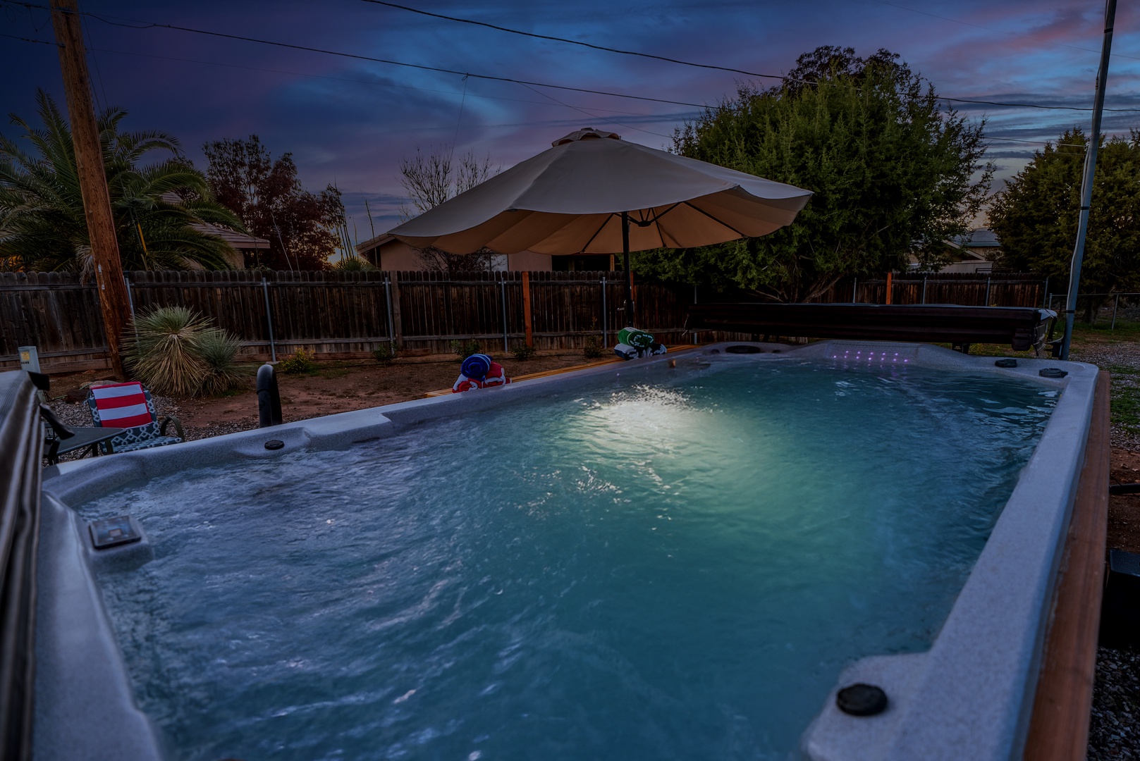 Unwind in your private hot tub under the evening sky, complete with umbrella shade and illuminated jets for the perfect relaxing soak.
