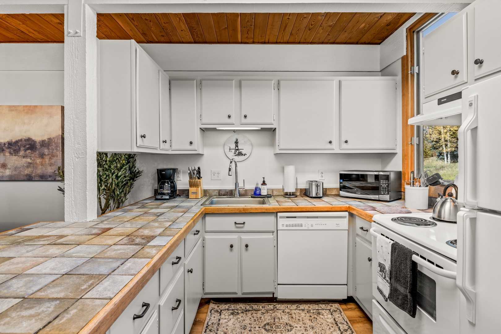 Your fully equipped kitchen welcomes you with warm wood ceilings, tile countertops, and everything you need to prepare meals during your stay, from coffee maker to full-sized appliances.
