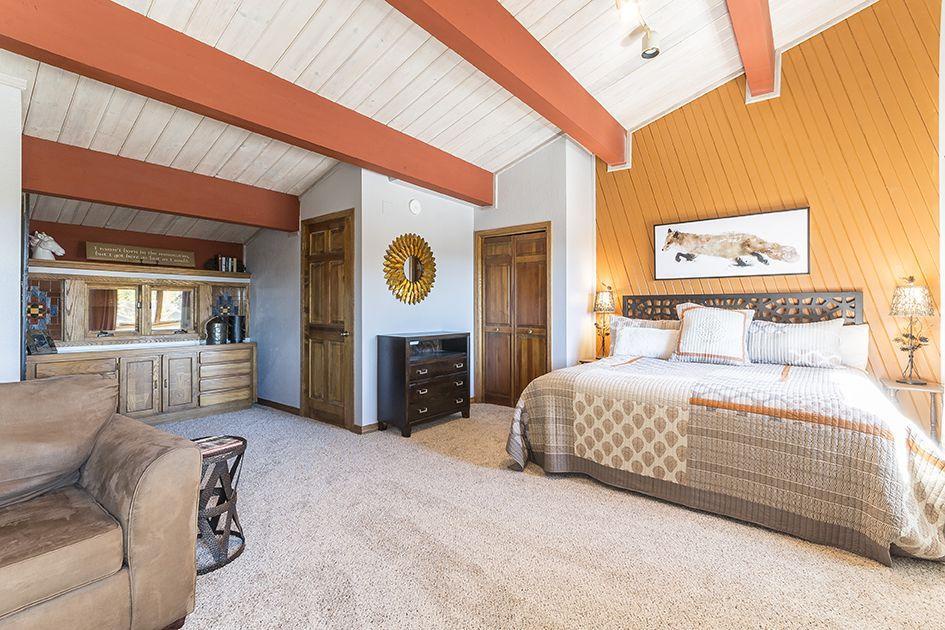 Your spacious bedroom blends rustic charm with cozy elegance, featuring vaulted ceilings, warm wood accents, and a plush king bed perfect for restful nights.