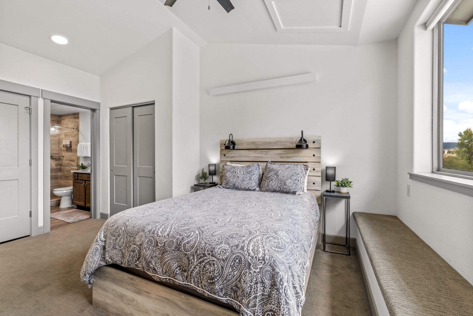 Relax in your peaceful bedroom with vaulted ceilings, warm modern touches, and a bright window that frames the natural beauty outside.