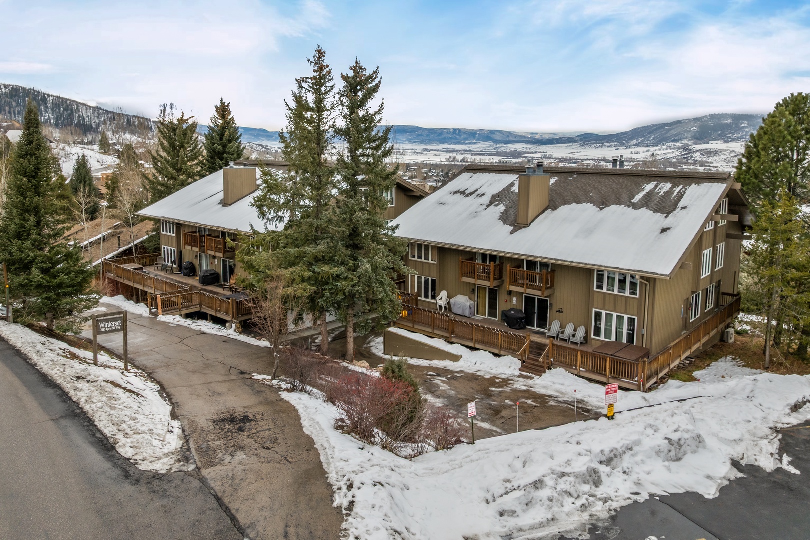 Mountain lodge nestled in snowy alpine valley with property buildings surrounded by evergreen forest.
