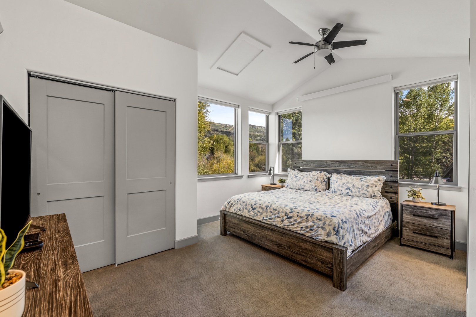 Wake up to lush greenery framed through your windows and drift off under a gentle ceiling fan. Your peaceful bedroom retreat features natural light from three sides and warm rustic wood tones that invite total relaxation.