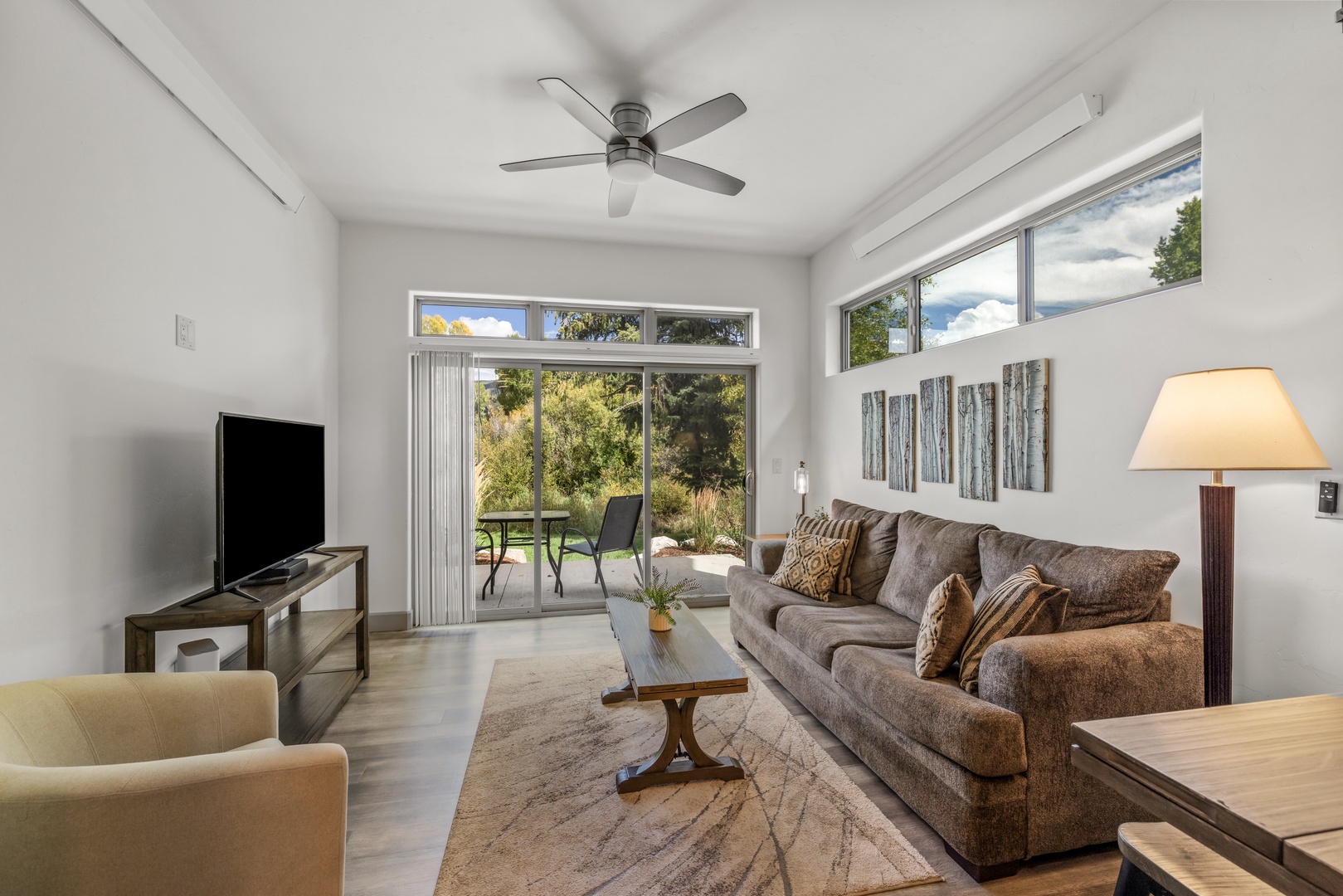Relax in this bright, airy living space with natural light streaming through glass doors opening to a private patio. Plush seating creates the perfect retreat.