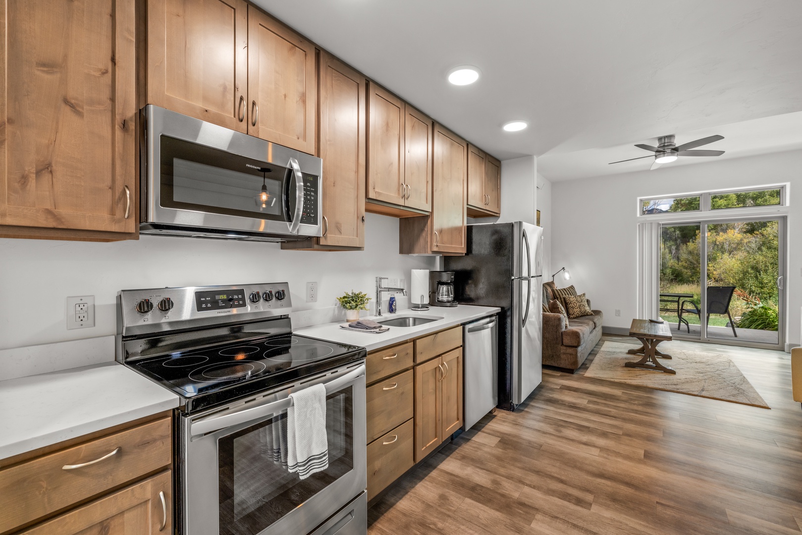 Your fully equipped kitchen flows seamlessly into the living area, where natural light spills through glass doors revealing a peaceful outdoor escape just steps away.