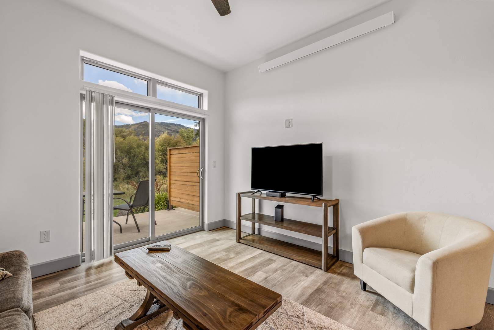 Unwind in a bright, modern living room where natural light pours through glass doors. Step outside to your private patio and soak in peaceful mountain views, while staying comfortable with air conditioning inside.