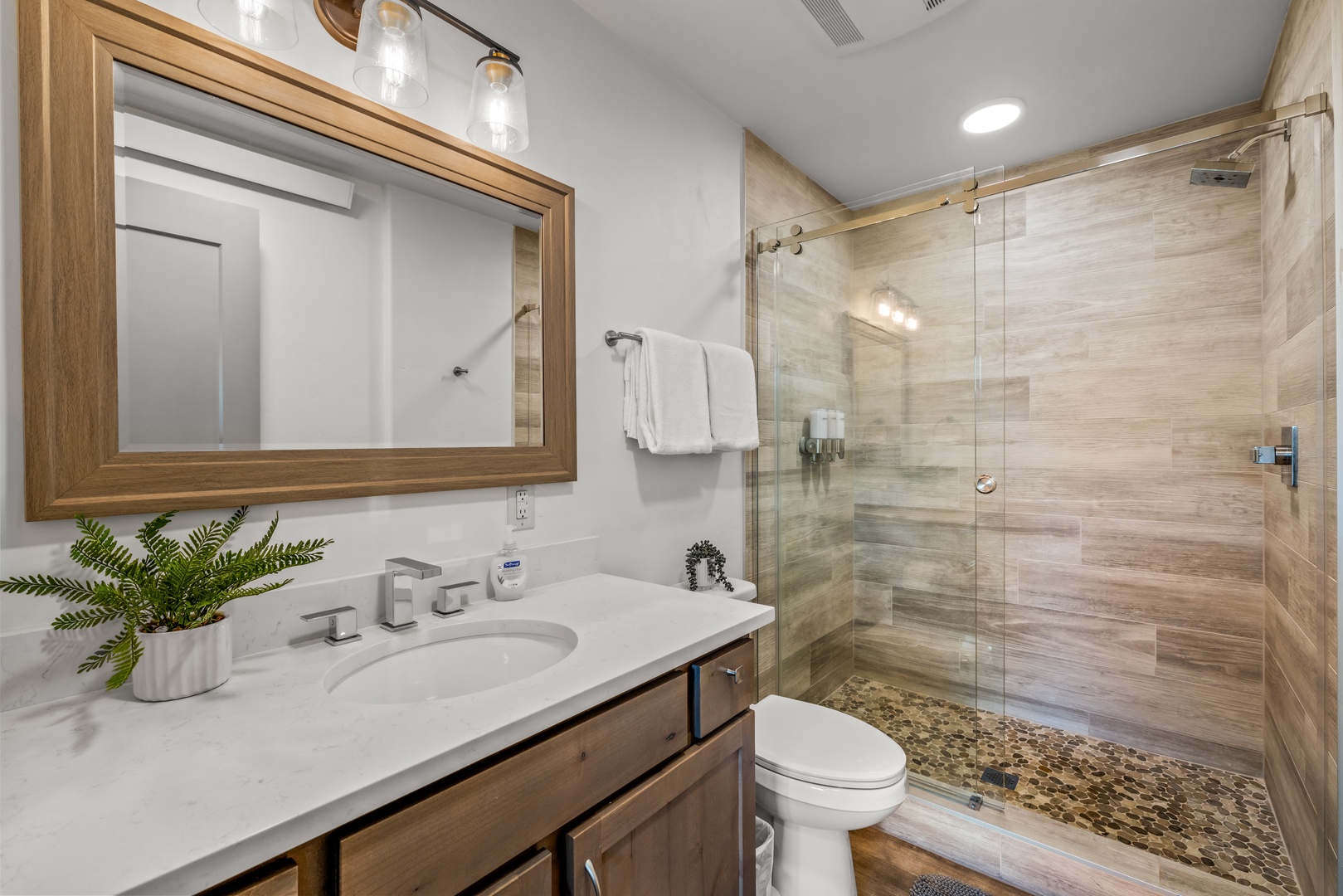 Refresh in your beautifully appointed bathroom with a spacious walk-in shower, warm wood accents, and a bright vanity area that makes every morning feel luxurious.